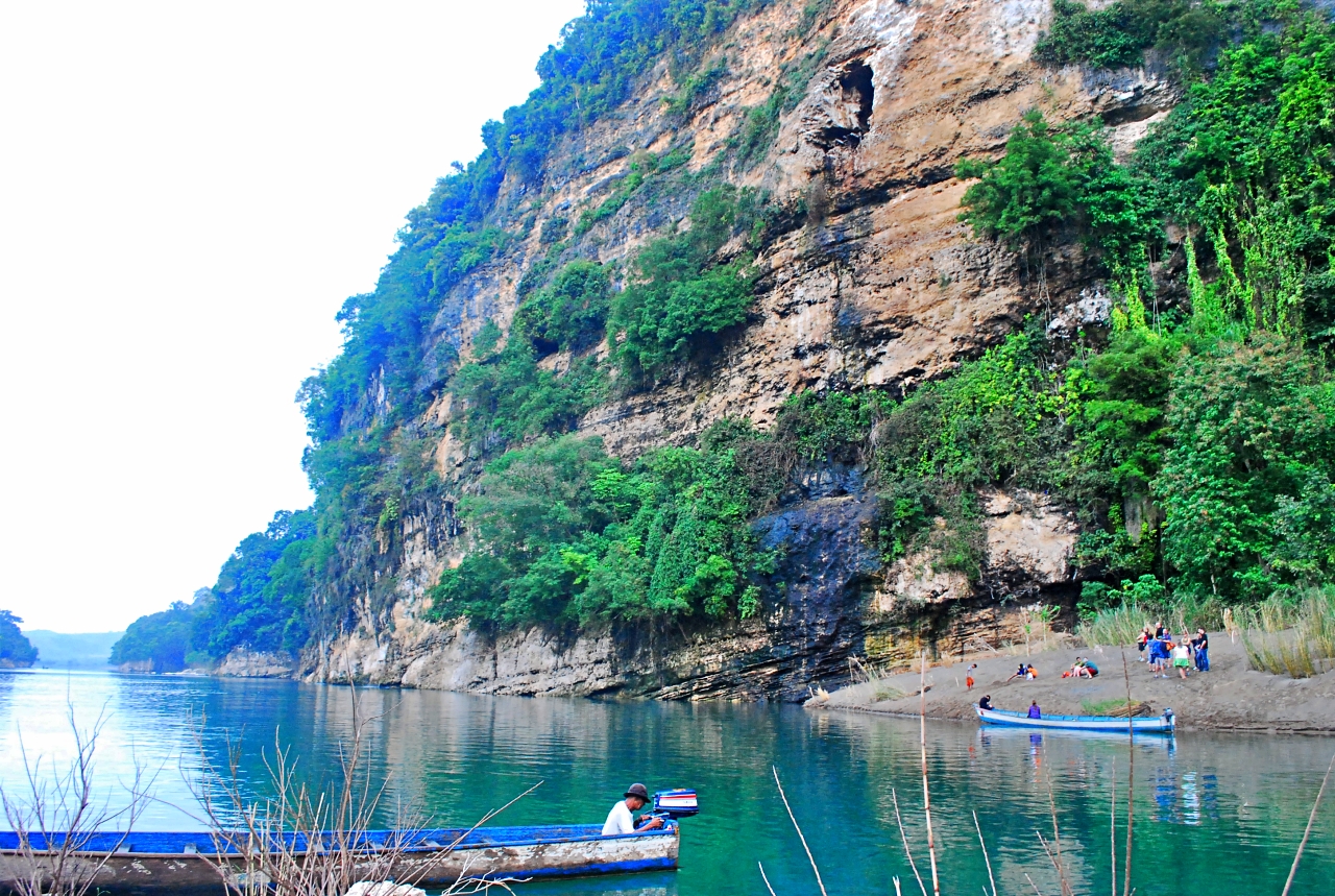 The Pinacanauan River is a pristine, deep-emerald waterway flanked by monumental limestone karst formations and dense, old-growth rainforests.